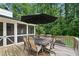 Outdoor dining on the deck, shaded by an umbrella, with views of the surrounding greenery at 6175 Weatherly Dr, Sandy Springs, GA 30328