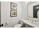 Elegant powder room featuring a pedestal sink, modern fixtures, and stylish decor at 6175 Weatherly Dr, Sandy Springs, GA 30328