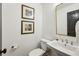 Powder room features a pedestal sink, modern faucet, and stylish artwork at 6175 Weatherly Nw Dr, Sandy Springs, GA 30328