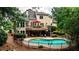 Spacious backyard boasts a deck, lower patio, swimming pool, and beautifully landscaped surroundings at 215 Settindown Ct, Roswell, GA 30075