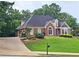 Lovely brick home on a well-manicured lawn with beautiful landscaping and a convenient driveway at 215 Settindown Ct, Roswell, GA 30075