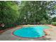 Inviting kidney-shaped pool with a brick border, surrounded by lush greenery and a secure fence at 215 Settindown Ct, Roswell, GA 30075