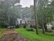 View of a brick two-story home with a black fence, lush greenery, and a driveway from the street at 423 Orchards Walk, Stone Mountain, GA 30087