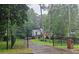 View of a brick two-story home with a black fence, lush greenery, and driveway from the road at 423 Orchards Walk, Stone Mountain, GA 30087