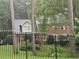 View of a brick two-story home with a black fence and lush greenery surrounding the property at 423 Orchards Walk, Stone Mountain, GA 30087