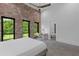 Bright main bedroom featuring exposed brick accent wall, high ceilings with fan, and view of the exterior greenery at 538 Main St, Palmetto, GA 30268