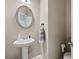 Well-lit half bathroom with a pedestal sink, decorative mirror, and neutral wall paint at 167 Diamond Ridge Ave, Canton, GA 30114