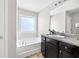 Well-lit bathroom featuring a soaking tub, vanity with counter space, and a large mirror at 167 Diamond Ridge Ave, Canton, GA 30114