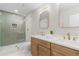 Bright bathroom featuring dual sink vanity, wooden cabinets, and glass shower with gold hardware at 6456 Wright Ne Rd, Atlanta, GA 30328