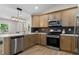 Well-lit kitchen with stainless appliances, wooden cabinets, stylish lighting fixture, and tile backsplash at 6456 Wright Ne Rd, Atlanta, GA 30328