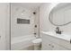 Modern bathroom features a white vanity, round mirror, and shower-tub combo with stylish marble tiling at 4451 Flat Shoals Pkwy, Decatur, GA 30034