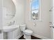 Half bathroom with pedestal sink, toilet, and a window at 4458 Dunblane Ave, Sugar Hill, GA 30518