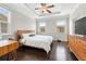 Bright bedroom featuring hardwood floors, a ceiling fan, and a wooden bedframe and dresser at 4458 Dunblane Ave, Sugar Hill, GA 30518
