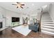Open concept living room with modern decor, kitchen view, fireplace and hardwood flooring at 4458 Dunblane Ave, Sugar Hill, GA 30518