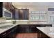 Close-up view of kitchen counter, featuring dark cabinets, granite countertops, a stainless steel microwave, and tile backsplash at 4547 Meadow Green Nw Ln, Acworth, GA 30101