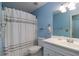 Charming bathroom with blue walls, a white vanity, toilet, mirror, and a shower with a decorative curtain at 5287 Wild Indigo Way, Acworth, GA 30102