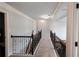 Hallway featuring modern lighting, neutral walls, and iron railing to staircase at 552 Warrenton Run Dr, Sugar Hill, GA 30518