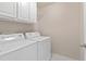 Bright laundry room with white washer and dryer, upper cabinets and patterned tile flooring at 1609 Vinery Se Ln, Mableton, GA 30126