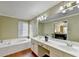 A bathtub and double vanity with white cabinets are featured in this bathroom with a view to the bedroom at 3034 Brookgreen Trl, Lawrenceville, GA 30043