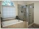 A well-lit bathroom boasts a frameless glass shower and a large soaking tub by a window at 11940 Wexford Club Dr, Roswell, GA 30075