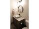 Elegant half-bathroom featuring a vessel sink, modern fixtures, and a round mirror, showcasing sophisticated design at 11940 Wexford Club Dr, Roswell, GA 30075