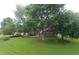 Beautifully landscaped front yard with green grass and mature trees surrounding a charming brick home at 11940 Wexford Club Dr, Roswell, GA 30075