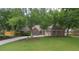 Charming brick home with a lush green lawn, mature trees, and a long driveway leading to a two-car garage at 11940 Wexford Club Dr, Roswell, GA 30075