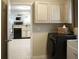 Well-lit laundry room features modern black washer and dryer and neutral cabinets with ample storage space at 11940 Wexford Club Dr, Roswell, GA 30075