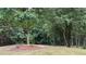 View of grassy backyard with mature tree and mulched planting area, offering privacy and natural beauty at 3066 Gem Creek Rd, Buford, GA 30519