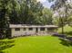Inviting white home with a lush green lawn, carport, and complemented by the surrounding verdant trees at 3620 W Lawrenceville St, Duluth, GA 30096