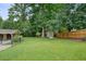 Large backyard featuring green grass, mature trees, shed, and wood fence at 4212 Worth Nw St, Acworth, GA 30101