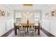 Dining room features a wood table with modern light fixture, wainscoting, and a large rug at 4972 Park Vale Dr, Sugar Hill, GA 30518