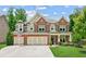Charming two-story brick home with a three-car garage and well-manicured lawn at 4972 Park Vale Dr, Sugar Hill, GA 30518