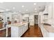 Open kitchen with stainless steel appliances, island with seating, white cabinetry and hardwood floors at 4972 Park Vale Dr, Sugar Hill, GA 30518