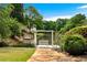 Beautiful backyard with lush landscaping, a serene pond, and a picturesque pergola swing at 5070 Riverlake Dr, Peachtree Corners, GA 30097