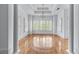 Bright living room with shiny hardwood floors, large windows with plantation shutters, and elegant chandelier at 5070 Riverlake Dr, Peachtree Corners, GA 30097