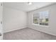 A carpeted bedroom featuring a window, door, and a ceiling light at 1528 Wembley Dr, Douglasville, GA 30134