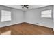 A cozy bedroom featuring a ceiling fan, window, hardwood floors, and neutral paint at 5440 Huron Dr, Lake City, GA 30260