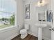 Cozy half bathroom featuring a pedestal sink, wood-look flooring, and natural light from the window at 3440 Hardy St, Duluth, GA 30096