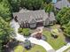 An aerial view showcases a brick and stone home on manicured lot with circular driveway and mature trees at 4634 Whitestone Way, Suwanee, GA 30024