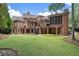 Stunning backyard with a brick home featuring a covered porch, balconies, and a lush lawn at 4634 Whitestone Way, Suwanee, GA 30024