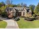 Beautiful stone and brick home with manicured lawn, curved driveway, and mature trees at 4634 Whitestone Way, Suwanee, GA 30024