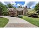 Stately brick and stone home with mature landscaping, circular driveway, and manicured lawn at 4634 Whitestone Way, Suwanee, GA 30024