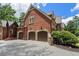 Side view of a brick home showcasing a spacious three-car garage and manicured landscaping at 4634 Whitestone Way, Suwanee, GA 30024