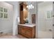 A wood vanity, sink, and mirror are featured in the main bath, adjacent to walk-in closet at 4634 Whitestone Way, Suwanee, GA 30024