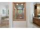 Hallway view to the main bath, showcasing a glass-enclosed shower and soaking tub with marble surround at 4634 Whitestone Way, Suwanee, GA 30024