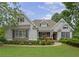 Charming home featuring a manicured lawn, complemented by lush landscaping, stone accents, and classic architectural details at 130 Holly Reserve Pkwy, Canton, GA 30114