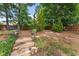 Serene backyard retreat with a stone pathway, mature trees, and cozy seating areas at 2213 Independence Ln, Buford, GA 30519