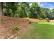 Beautiful backyard with a landscaped hill, lush lawn, and mature trees at 2213 Independence Ln, Buford, GA 30519