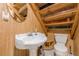 Cozy bathroom with wood paneling, a pedestal sink, toilet, and decorative shelves, offering a rustic and charming atmosphere at 5848 Kingswood Ct, Norcross, GA 30093